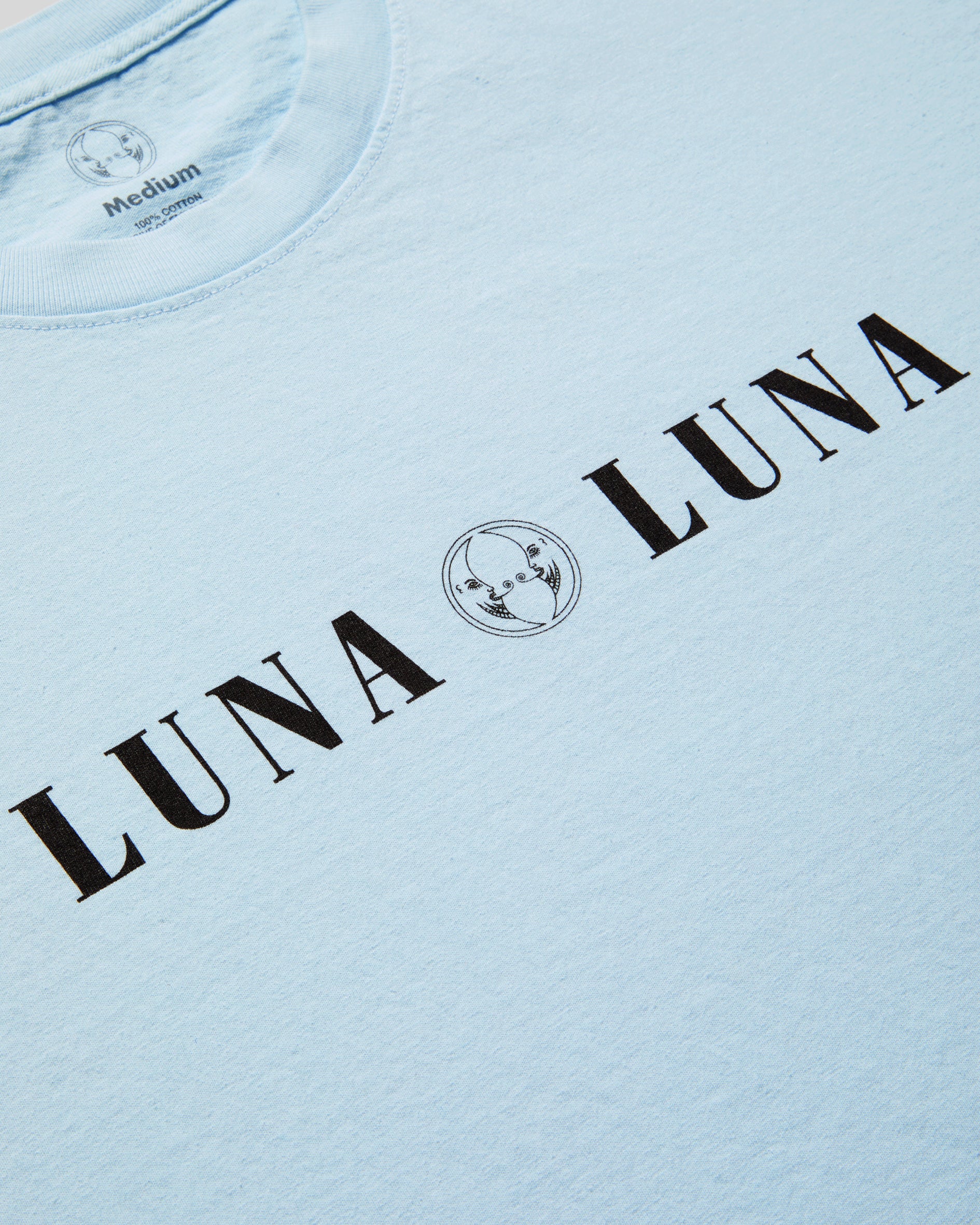 1987 Luna Luna T-Shirt in Baby Blue. Close up photograph of baby blue t-shirt with black text at chest that reads "LUNA LUNA"